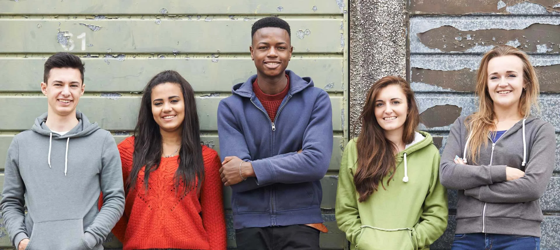a group of five teenagers stand in front of a garage door